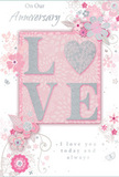 This anniversary card offers a gentle celebration of enduring romance, like an intimate dinner at home in Purley where every detail has been thoughtfully arranged. The design is built around a soothing palette of pastel pinks and silvery greys, creating a calm, cocooning atmosphere. At the centre, the word "LOVE" is spelled out in soft, raised glitter, each letter smooth and slightly rounded, reflecting light in a subtle, pearly sheen. The "O" is replaced by a shimmering silver heart, textured to stand out distinctly from the surrounding letters. It appears almost like a tiny keepsake charm nestled within the word. Framing this focal point, delicate blooms in blush, mauve, and pale ivory unfurl with an almost watercolour softness, their edges gently blurred as though painted by hand. The flowers and fine vines radiate outward, their curves evoking the graceful sweep of stems in a hand-tied bouquet prepared for an anniversary delivery near Woodcote Valley Road. Tiny flourishes-scattered petals, tender swirls, and the lightest suggestion of butterflies in mid-flight-add motion and whimsy, reminiscent of an English spring garden waking after a light rain. The background remains a soft, dusty pink that enhances the silver details and keeps the eye focused on the central heart. Above and below the floral arrangement, the phrases "On Our Anniversary" and "I love you today and always" are written in refined, understated script, giving the card a polished yet heartfelt finish. The overall composition carries a lovely sense of occasion: not loud or showy, but as warm and meaningful as receiving a fresh bouquet from a trusted Purley florist, quietly honouring a shared journey through the years.